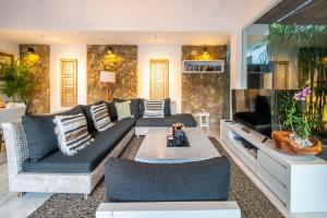 Lotus Luxury Villa Seminyak في سمينياك: غرفة معيشة مع أريكة وتلفزيون