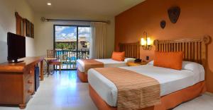 ein Hotelzimmer mit zwei Betten und einem Fernseher in der Unterkunft Catalonia Yucatan Beach - All Inclusive in Puerto Aventuras