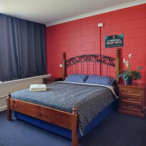 a bedroom with a wooden bed with a red wall at Port Adelaide Backpackers in Adelaide