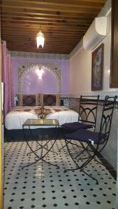 een slaapkamer met een bed en een glazen tafel en stoel bij Dar Nour Fes in Fès