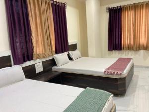 a room with two twin beds and curtains at Hotel Sai viraj palace in Shirdi