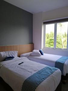 2 camas en una habitación con ventana en The Holiday Guest House, en Tanjung Pandan