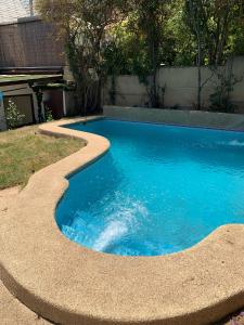 uma pequena piscina com um caminho curvado à sua volta em Agradable casa con piscina, cerca del mall. em Santiago