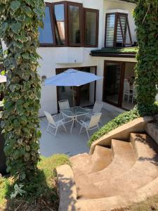 eine Terrasse mit einem blauen Sonnenschirm, Stühlen und einem Tisch in der Unterkunft Agradable casa con piscina, cerca del mall. in Santiago