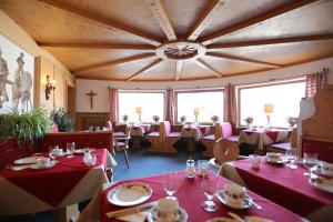 a dining room with red tables and chairs and a large ceiling at Gästehaus Heimgarten in Bad Wiessee