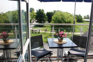 un patio con 2 mesas y sillas con flores. en Residenz am Hafen Neptunsuite, en Ahrenshoop