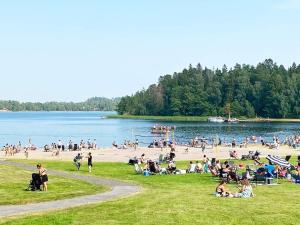 grupa ludzi siedzących na plaży nad jeziorem w obiekcie Holiday home JERNA w mieście Järna