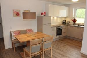 una cucina con tavolo e sedie in legno e una cucina con armadietti bianchi di Aquamarin Ostseetraumsuite 08 a Neuhaus