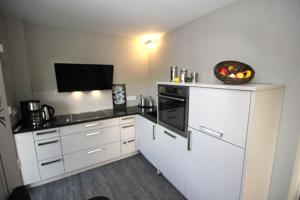 a kitchen with white cabinets and a bowl of fruit on the counter at Aquamarin Ostseetraumsuite 10 in Neuhaus