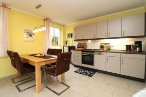 a kitchen with a wooden table and chairs in it at Residenz am Hafen Boddensuite in Ahrenshoop +9 photos