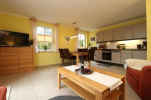 a living room with a couch and a table and a kitchen at Residenz am Hafen Boddensuite in Ahrenshoop