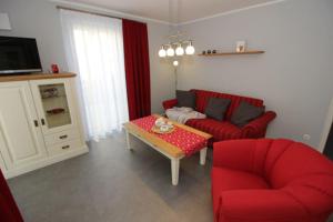 Sala de estar con sofá rojo y mesa de centro en Aquamarin Ostseetraumsuite 01, en Neuhaus