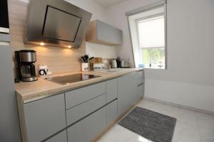 uma cozinha com armários brancos, um lavatório e uma janela em Aquamarin Ostseetraumsuite 12 em Neuhaus