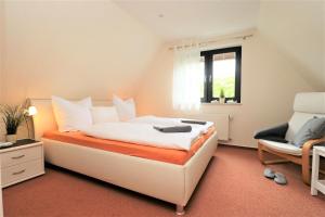 een slaapkamer met een wit bed en een stoel bij Ferienhäuser Strandhaus Leo in Dierhagen