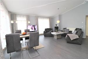 a living room with chairs and a table and a tv at Meerquartier App 08 in Neuhaus