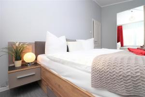 a bedroom with a large white bed and a lamp at Meerquartier App 08 in Neuhaus