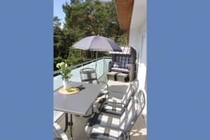 une terrasse avec une table, des chaises et un parasol dans l'établissement Strandhaus Strandhaus, App 01, à Dierhagen