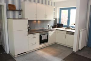 a kitchen with white cabinets and a stove top oven at Haus Ostseeidyll, App 01 in Neuhaus