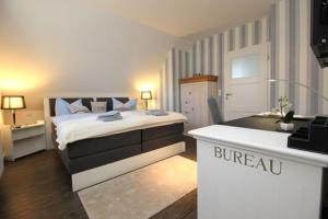 a white bedroom with a bed and a desk at Haus Ostseeidyll, App 01 in Neuhaus
