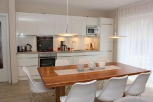 a kitchen with a wooden table and white chairs at Strandvilla Birkenallee Haus Sommerlicht in Neuhaus