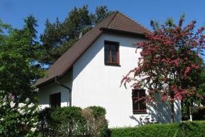 Ferienhäuser Ferienhaus Xenia في ويك: بيت ابيض بنوافذ حمراء وشجرة