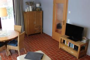 Ferienhäuser Ferienhaus Xenia في ويك: غرفة معيشة مع طاولة وتلفزيون وطاولة وكراسي