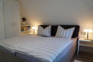 a large bed in a room with two tables and two lamps at Ferienhäuser Reethaus am Deich in Dierhagen