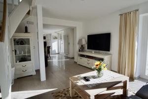 a living room with a couch and a tv at Ferienhäuser Reethaus am Deich in Dierhagen