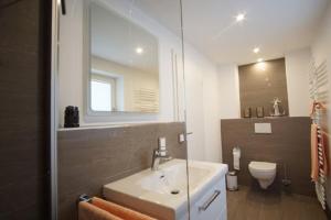 a bathroom with a sink and a toilet and a mirror at Ferienhäuser Reethaus am Deich in Dierhagen +21 photos