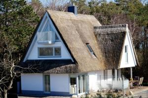 a house with a thatched roof with a porch at Ferienhäuser Reethaus am Deich in Dierhagen