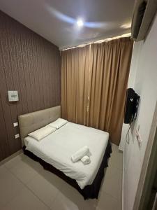 One Point Hotel @ Airport (Kuching) في كوتشينغ: سرير صغير في غرفة صغيرة مع تلفزيون