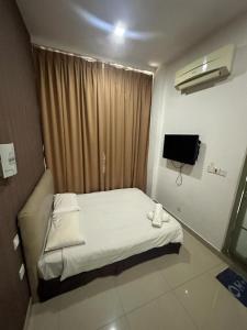 Dormitorio pequeño con cama y TV en One Point Hotel @ Airport (Kuching) en Kuching
