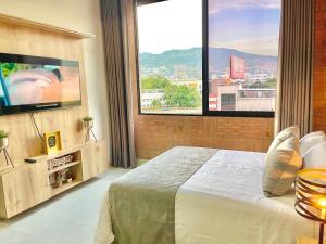 ein Schlafzimmer mit einem großen Bett und einem großen Fenster in der Unterkunft APARTAMENTOS EN LAURELES, MEDELLÍN in Medellín