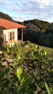 una pequeña casa en un patio con un arbusto en Pousada Canto da Lua - charme e vista incrível, en Carrancas