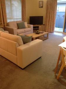 ein Wohnzimmer mit 2 weißen Sofas und einem TV in der Unterkunft RELAX on Ronald Street in Devonport