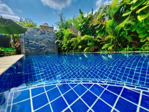a swimming pool with a blue tile floor and plants at Bed & Bedzzz in Siem Reap