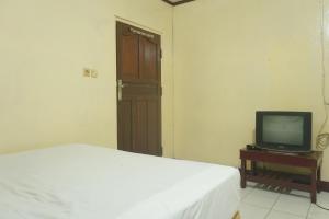 的住宿－SPOT ON 92549 Wisma Ribas Syariah，一间卧室配有一张床和一张桌子上的电视