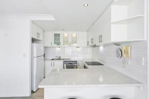 een witte keuken met een groot wit aanrecht bij Cosmopolitan - Hosted by Coastal Letting in Gold Coast