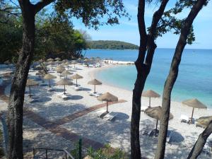 ein Strand mit Sonnenschirmen und Stühlen und das Meer in der Unterkunft Alba Sanja in Funtana