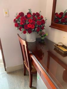 un vase de roses rouges assis au-dessus d'une table dans l'établissement Thịnh Nhàn motel, à Móng Cái