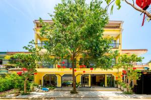 a yellow building with a tree in front of it at Chillax Old Town Villa in Hoi An