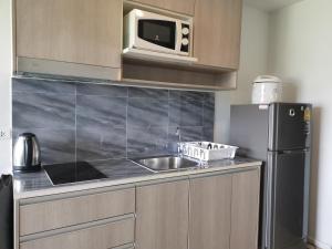 a kitchen with a sink and a microwave and a refrigerator at 5 Floor - Centrio Condominium in Phuket Town - 30 mins to beaches in Phuket Town