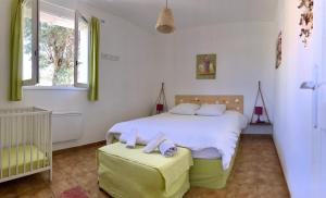 een slaapkamer met een wit bed en een wieg bij Gîte L'oliveraie d'Aniane 7 personnes in Aniane