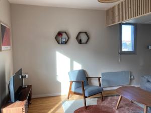 a living room with a table and a chair and a tv at Studio proche plage balcon et parking in Deauville