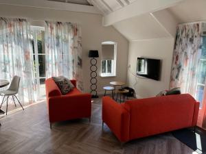 a living room with two red chairs and a table at Villa Victoria with sauna in Ermelo in Ermelo
