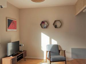 a living room with a chair and a television at Studio proche plage balcon et parking in Deauville