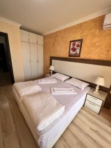 a bedroom with a large bed with white sheets at OLYMP Aparthotel in Sveti Vlas