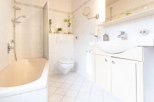 a white bathroom with a tub and a sink and a toilet at Haus Schwanensee PLÖNI 12 in Bosau