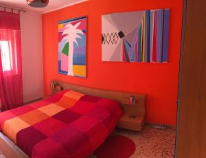パレルモにあるB&B La Galleriaのオレンジ色の壁とカラフルな絵画が特徴のベッドルーム1室