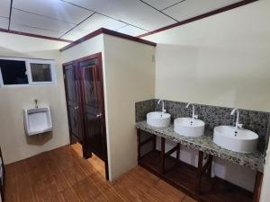 un bagno con tre lavandini e un orinatoio di Fenix Hotel & Hostel a Útila